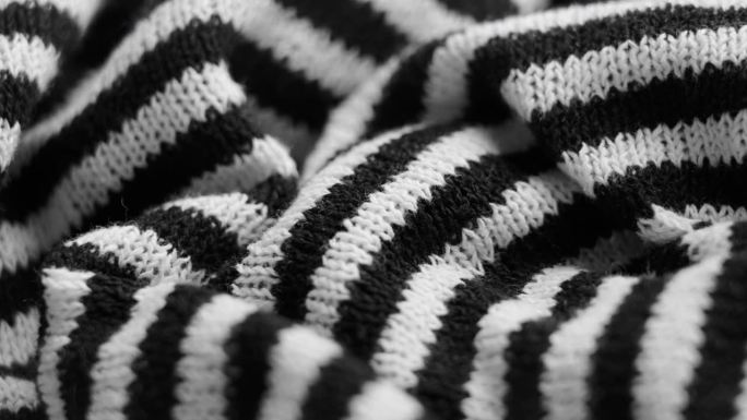 黑白条纹针织时尚面料与皱纹。抽象的褶皱图案。宏。旋转。