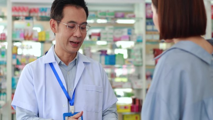 亚洲男药剂师在药房讲解如何正确服药治疗疾病。卫生保健中心