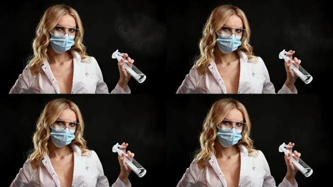 年轻的商务女员工戴着面部防护医用口罩，将瓶子里的抗菌消毒凝胶涂在手上，开始在现代办公室里使用电脑，预