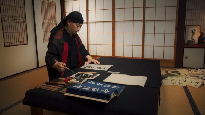 日本男性书法艺术家用汉字绘制艺术符号。禅师或和尚用墨笔练习传统的美丽的纸上书写艺术
