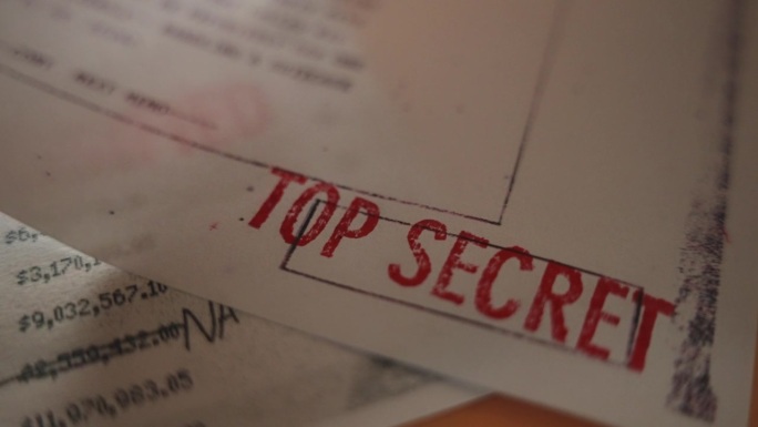 桌子上放着一份看起来像官方机密的文件，上面盖有最高机密的红章