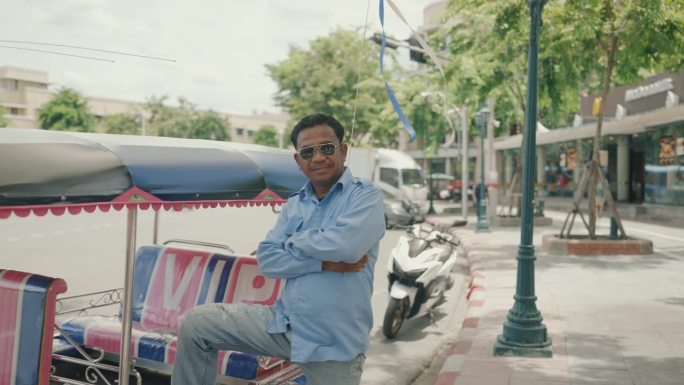 微笑的亚洲老年出租车司机对当地的嘟嘟车充满信心和自豪。