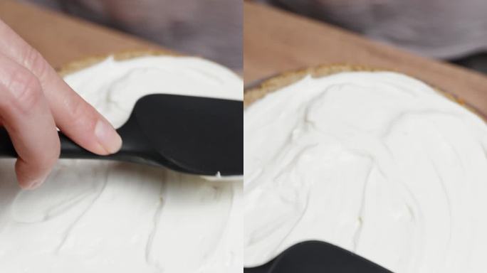 从上面看，糕点师正在把白奶油涂在蛋糕层上。垂直视频。