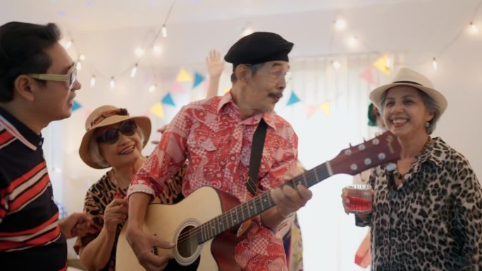 在一个家庭聚会上，当朋友们一起跳舞时，快乐的老人在弹吉他。
