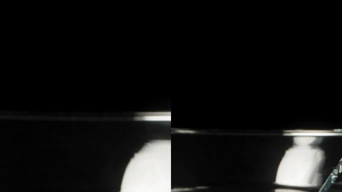 一个破碎的马提尼鸡尾酒杯在黑色背景上，多莉滑块极端特写。垂直视频。