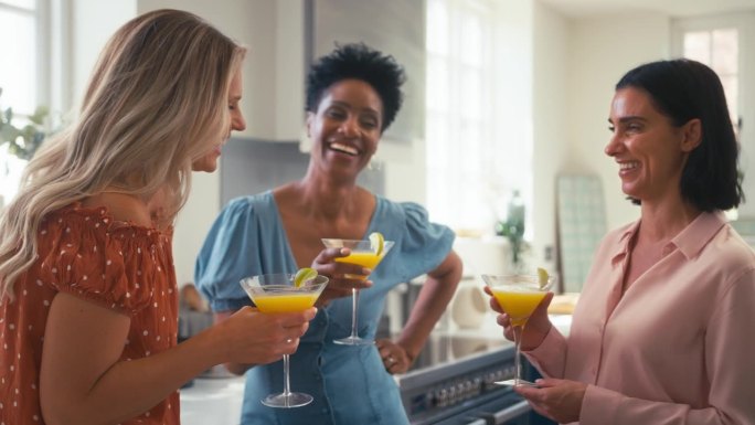 三个成熟的女性朋友在家里一起在厨房喝鸡尾酒