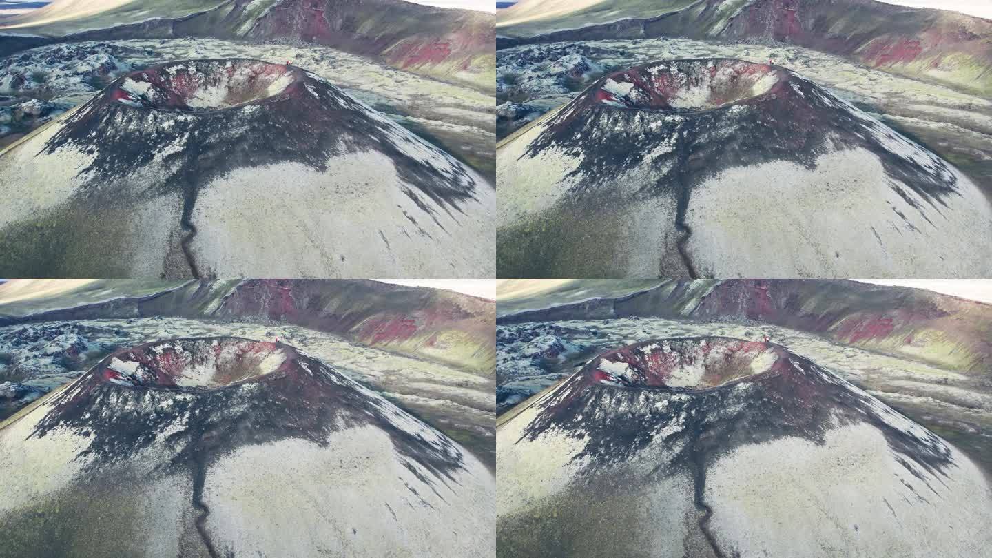 航拍:在一个晴朗的日子里，冰岛高地上，绿色和红色的休眠火山和充满活力的火山环视。有些人站在火山的山顶