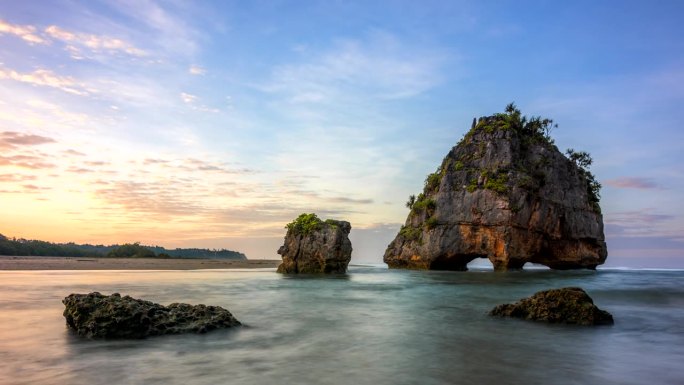 延时日出场景移动的云和岩石形成的碰撞波在Pantai Watu Malandong，西松巴，印度尼西