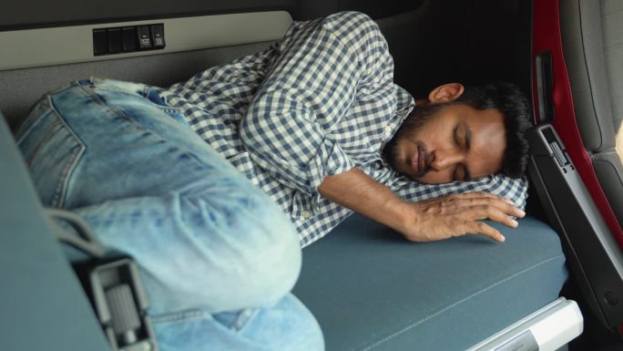 印度卡车司机在长途加班后睡在自己的小屋里