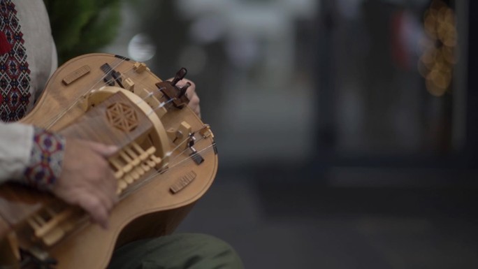 《人的近景》中，他正在演奏一种手摇弦乐器，这种乐器是通过一个带曲柄的松香轮摩擦琴弦而发出声音的。