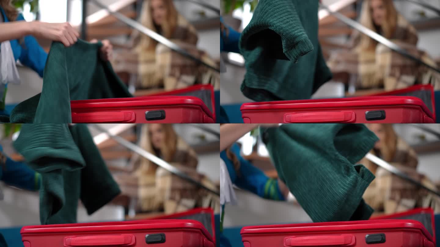 特写红色旅行包，女性的手把行李放在里面，模糊的十几岁的女孩坐在背景中。无法辨认的空姐母亲正在家里收拾