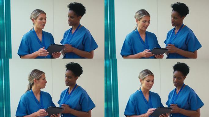 两个成熟的女医生穿着手术服拿着电子平板电脑在医院讨论病人的记录