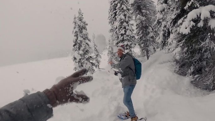 冬雪覆盖的森林里打雪球。寒假。一名男子向摄像机扔雪球