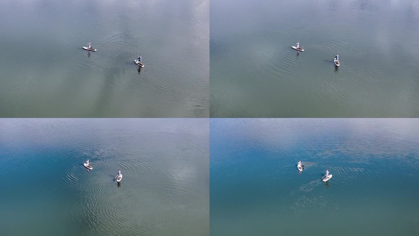 空中轨道围绕着两个人在正午的湖面上玩桨板