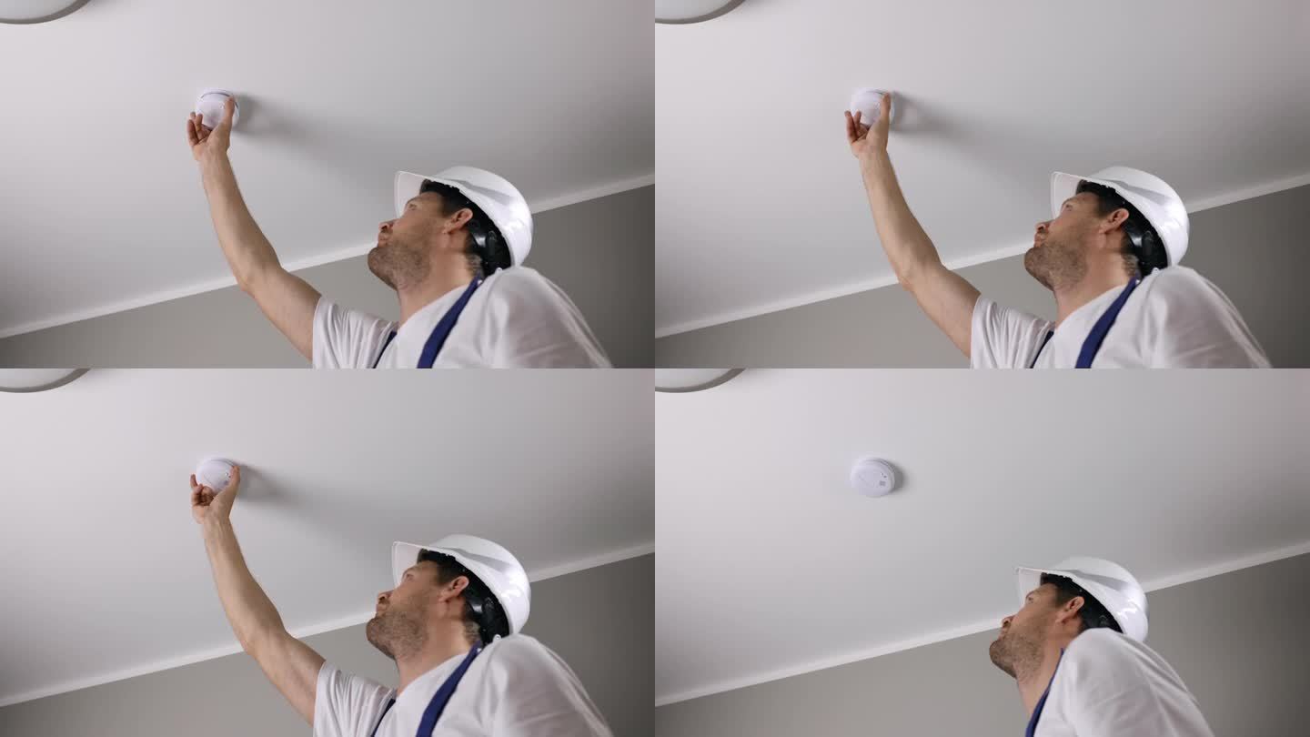 消防安全工程师在房屋天花板上安装光电感烟探测器。家庭安全及火灾报警系统