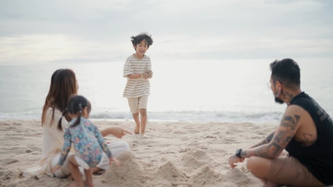 一张亚洲家庭坐在沙滩上的照片。他们在一起玩，堆沙堡。