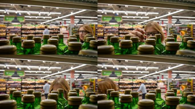 一位年轻女子从超市的货架上拿了一瓶绿色的矿泉水