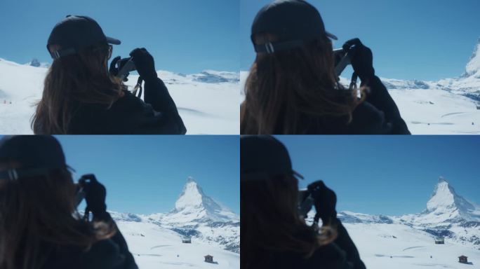 一个快乐的年轻女子在瑞士雪山度假的空闲时间拍照的后视图。