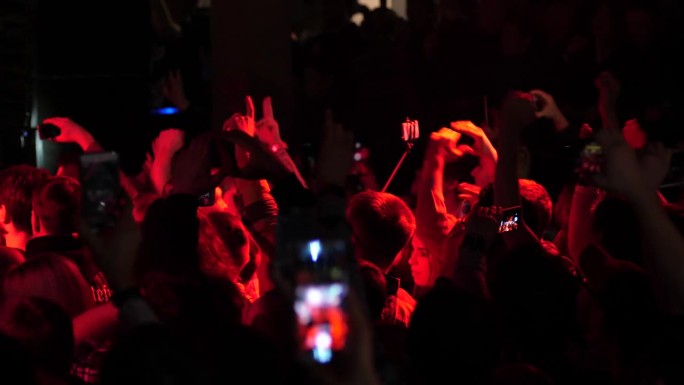 免费音乐会，人群，歌迷，欢快地跳舞，举手，在闪光灯下拍摄手机视频