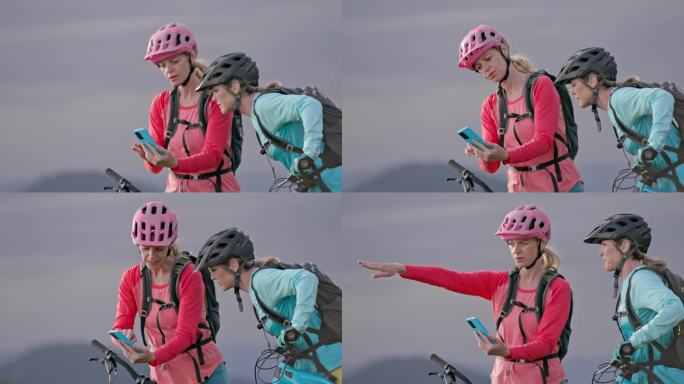两个女山地自行车手看着智能手机，指着附近的小路