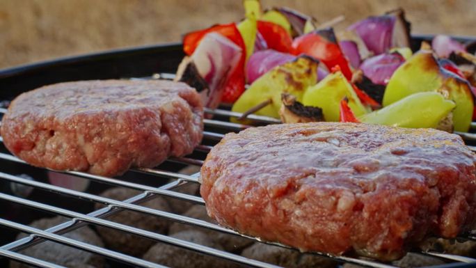 烤好的肉排用刷子涂上香油，蔬菜串在背景上。