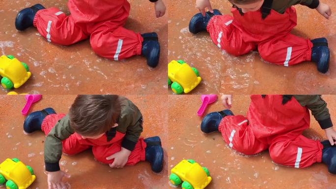 宝宝好奇地在泥泞的水坑里戏水，探索水和泥的本质。两岁男童(2岁)