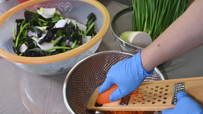 制作传统韩国菜泡菜的过程。一位戴着手套的妇女正在准备制作泡菜所需的各种材料。