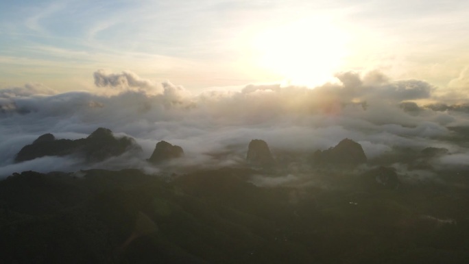 在日出时与雾流一起飞越局部山脉。航拍视频