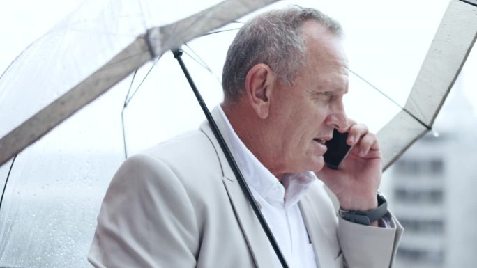 电话里，老人和商人在城市里打着雨伞，以防下雨。智能手机，通话，户外遮阳伞，冬天ceo在手机上讲话时用
