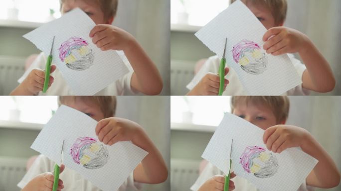 可爱的男孩在课堂上剪格子纸的彩绘