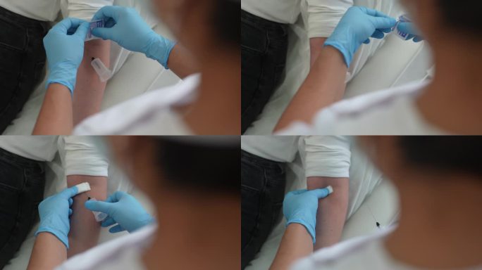 从静脉抽血后，无法辨认的护士将一块酒精棉絮放在手上的特写镜头。采血过程结束。