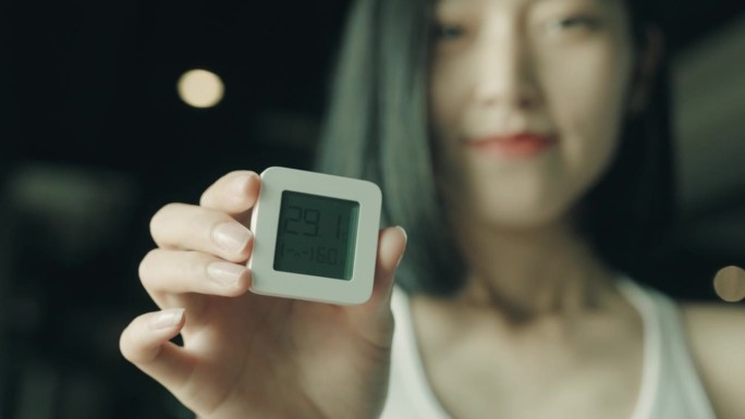 一个年轻的亚洲女人拿着电子体温计