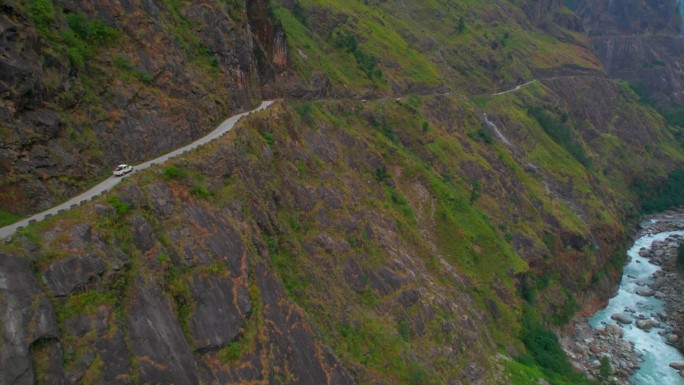 空中俯瞰四驱车行驶在狭窄危险的砾石道路。自驾游在喜马拉雅山探险旅行。安纳普尔纳峰电路。独特的管理理念