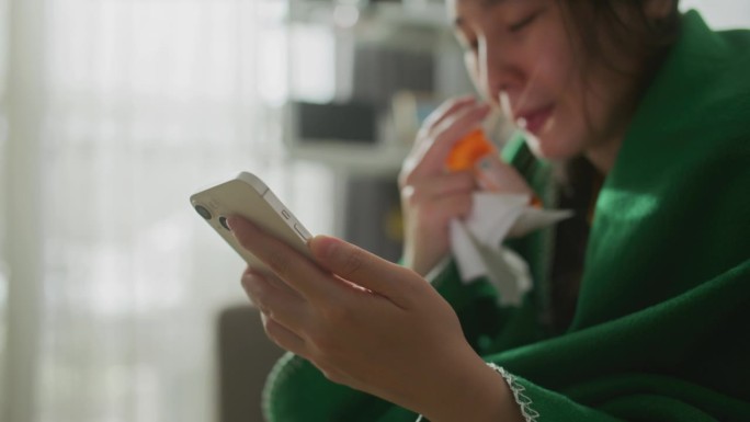 年轻的亚洲女子拿着药瓶，用手机打电话