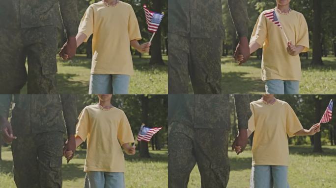 孩子手持美国国旗，与身穿军装的父亲同行