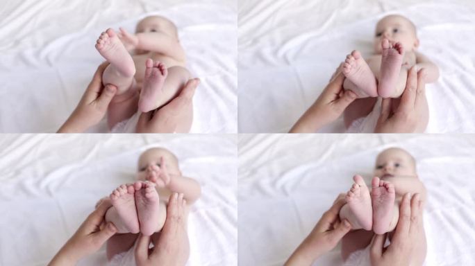 妈妈的手捧着婴儿的腿，在婴儿床的白色棉质床上，卫生又照顾又照顾着新生儿。
