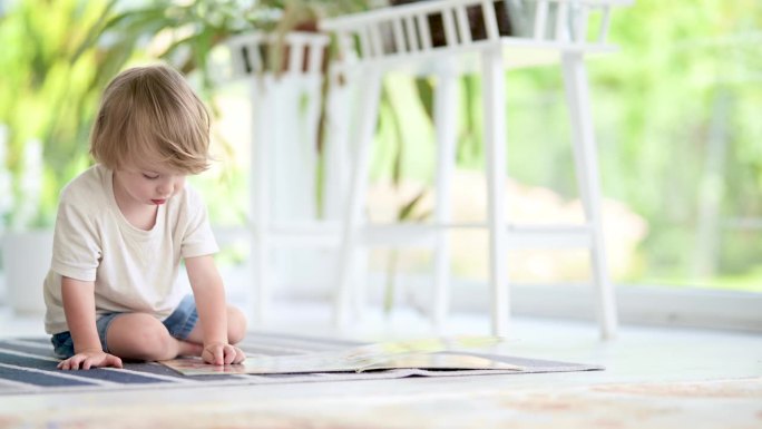 可爱的小男孩在家里地板上看书。日间护理创意活动。孩子们玩得很开心。教育学习游戏。家庭休闲室内。