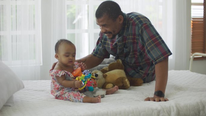 快乐的非裔美国爸爸在卧室里照顾他的孩子