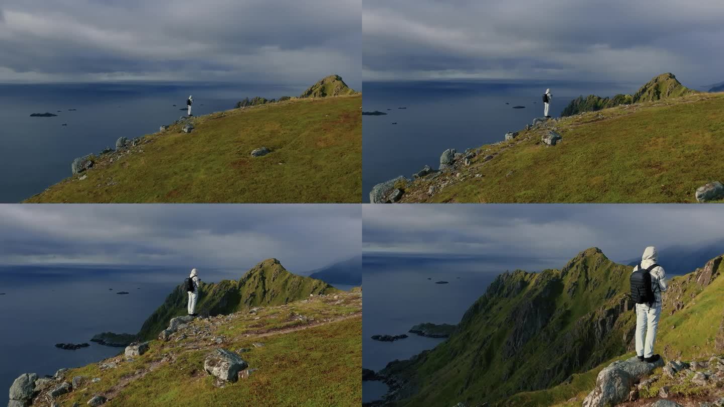 史诗般的鸟瞰图，年轻的男性背包客站在石头上，从峡湾的山顶观察挪威海的景色