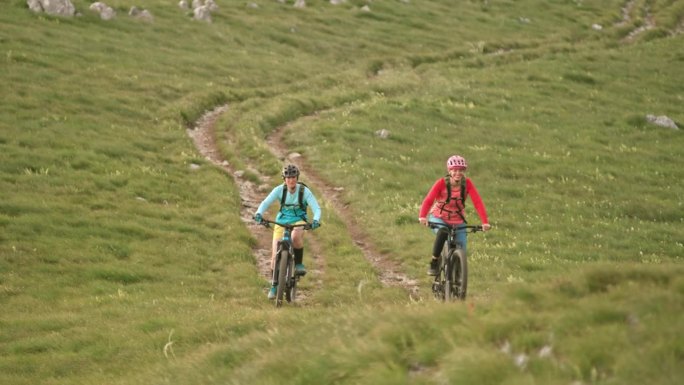 两个女人骑着电动山地车在山道上聊天