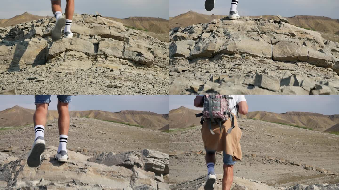 穿着白袜子和白鞋子的游客的强壮的男性腿自信地跳过一个有目的的人走向目标的石头景观。独自徒步旅行。