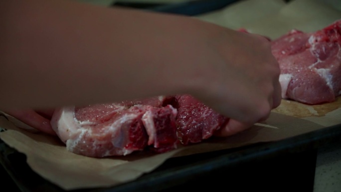 一位妇女把生肉放在烤纸上。