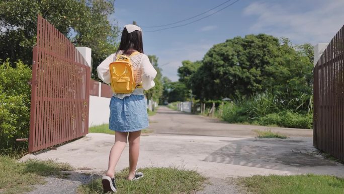 一个可爱的女孩正走出家去上学