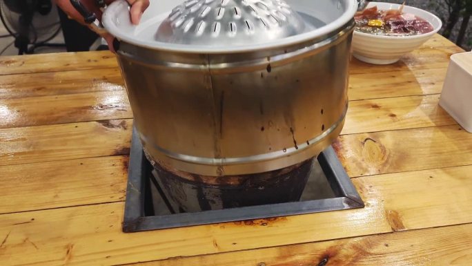 餐厅工作人员正在将木炭烤架放入燃烧器隔间，并将其与泰国热烧烤锅一起放置