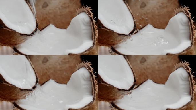 椰奶从断椰子的两半流出来，慢镜头。