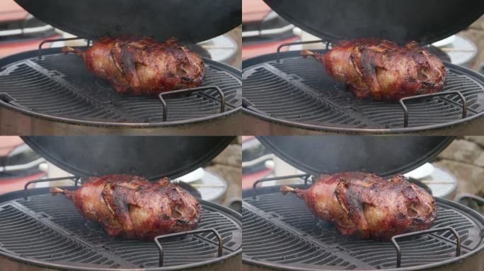 特写镜头打开木炭便携式烤架烧烤整只鸭子与模糊的背景