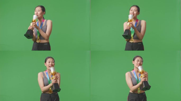 获得金牌的亚洲女子在金杯上唱歌庆祝自己成为首个冠军，绿幕背景在演播室