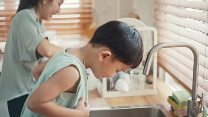亚洲男孩在母亲的帮助下用生理盐水注射器冲洗鼻腔