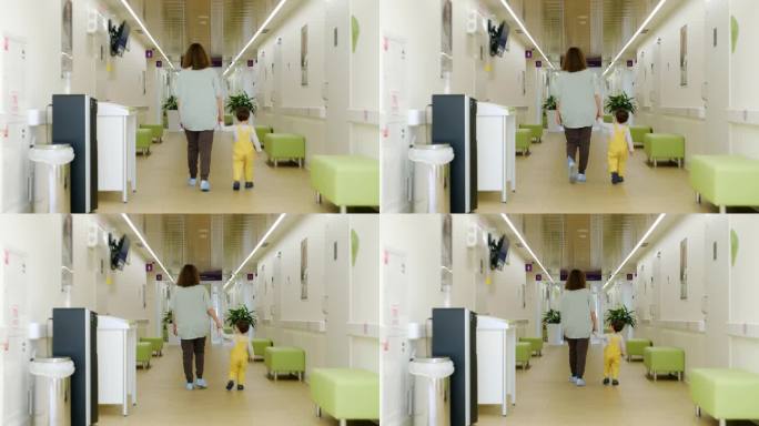孩子和母亲手拉着手走在医院长长的走廊上。两岁儿童(两岁男童)