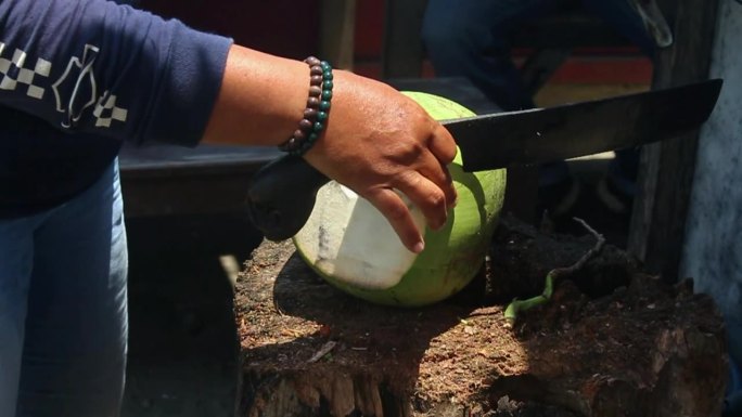 一个卖饮料的人正在切椰子